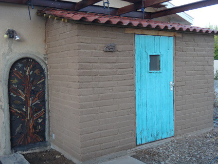 An adobe addition with bright turquoise door